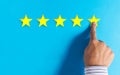 Hand choosing 5 stars rating on blue background Royalty Free Stock Photo