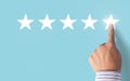 Hand choosing 5 stars rating on blue background - Positive feedback