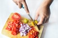 Hand chopping an orange on a plate full of vegetables