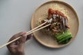 Hand with chopsticks for eat. Dry Yellow noodles with Grilled Duck and Crispy Pork. Royalty Free Stock Photo