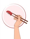 A hand with chopsticks holds a sushi with tuna. Asian kitchen elements with sushi and wooden chopsticks.