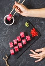 Hand with chopsticks on sushi set with soy sauce on black stone desk. Royalty Free Stock Photo