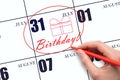 The hand circles the date on the calendar 31July, draws a gift box and writes the text Birthday. Holiday. Royalty Free Stock Photo