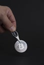 Hand with clamp holding silver bitcoin coin on black background. Cryptocurrency concept. Royalty Free Stock Photo