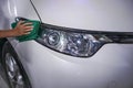 Hand cleaning car headlight on a white car Royalty Free Stock Photo