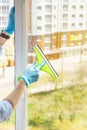 Hand cleaning glass window pane with detergent and rubber aluminum wiper. A female hands in bright blue gloves washes the windows Royalty Free Stock Photo