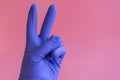 Hand with cleaning glove making peace. Hand in a rubber glove on a pink background