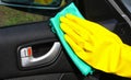 Hand cleaning interior car door panel with a green microfiber cloth in yellow gloves. Royalty Free Stock Photo