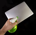Hand cleaning a laptop with a spray bottle sanitizer. Royalty Free Stock Photo