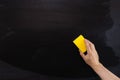 Hand cleans the chalk Board with a yellow sponge