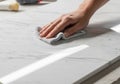A hand cleans a marble countertop with a soft, gray cloth. The surface Royalty Free Stock Photo