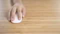 Hand Clicking on white computer mouse on the wooden desk