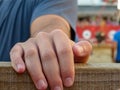 hand clinging to the wooden trench with bull in the background blurred of bulls