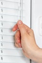 Hand closes the blinds on white plastic window Royalty Free Stock Photo