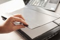 A hand closing a flatbed scanner with a laptop computer in the background. Selective focus