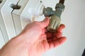 Hand closing the valve of a hot water radiator. Energy conservation, home heating