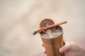 Hand with cocktail, Alcoholic drink with ice, orange and cinnamon on the beach Royalty Free Stock Photo