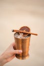 Hand with cocktail, Alcoholic drink with ice, orange and cinnamon on the beach Royalty Free Stock Photo