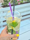 hand with Cold refreshing limonade, mojito or gin tonic in glass, with fresh mint and ice cubes, lime and lemon on Royalty Free Stock Photo