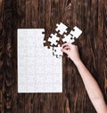 Hand collecting white puzzle on brown background