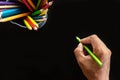 Hand with color pencils, on black background Royalty Free Stock Photo