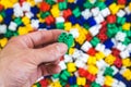 Hand with colorful plastic bricks of green color and details of toys on a colorful background Royalty Free Stock Photo