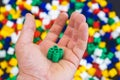 Hand with colorful plastic bricks of green color and details of toys on a colorful background Royalty Free Stock Photo