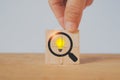 Hand complete square wood cube block with magnifying glass and brighten lightbulb icon for idea, brainstorming concept Royalty Free Stock Photo