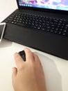 Hand with computer mouse beside laptop keyboard on a white background