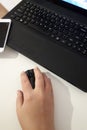 Hand with computer mouse beside laptop keyboard on a white background