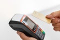 A hand confidently holds a golden credit card over a modern contactless payment terminal Royalty Free Stock Photo