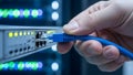 Hand Connecting Blue Ethernet Cable to Network Switch in Server Room Royalty Free Stock Photo