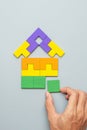 Hand connecting Home shape block with colorful wood puzzle pieces on gray background. logical thinking, business logic, solutions Royalty Free Stock Photo