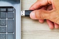 Hand connecting USB cable to laptop computer on wooden desk Royalty Free Stock Photo