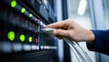 Hand Connecting White Ethernet Cable to Network Switch in a Busy Server Room Environment Royalty Free Stock Photo