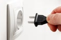 Hand connects an american electric plug into a white european socket or white wall outlet Royalty Free Stock Photo