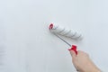 Hand with a construction roller in the process of priming the wall. The concept of renovation and decoration of the room.