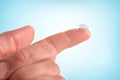 Hand with contact lens on finger with isolated blue background Royalty Free Stock Photo