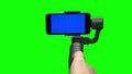 Hand controlling steadicam stabilizer with the blue screen on smartphone.