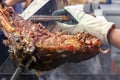 Hand cook with a knife and forceps cut into pieces the ready lamb on a spit over hot coals Royalty Free Stock Photo