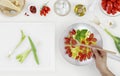 hand cooking fry and mix tomatoes sauce above saucepan with cutting board and food ingredients on kitchen white worktop, copy spa Royalty Free Stock Photo