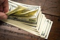 Hand counting pile of one hundred US banknotes on wooden table background. Cash of hundred dollar bills, paper money currency