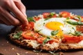 hand cracking an egg onto a cauliflower pizza