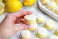 hand cracking open a lemon macaron to display the cream filling