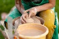 Hand craft making pottery on wheel. Female hands mold ceramic plate from clay pot Royalty Free Stock Photo