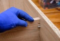 Hand of craftsman in protective glove during wood furniture assembly from medium-density fibreboard