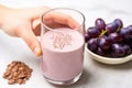 hand creating a pattern of flaxseed on a thick grape smoothie