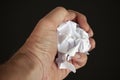 Hand curling a piece of paper on black background. Close up image