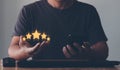 Hand of the customer or client holding the stars to complete five stars. giving a five-star rating on mobile smartphone Royalty Free Stock Photo