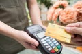 Hand of customer paying with contactless credit card in flower shop. Royalty Free Stock Photo